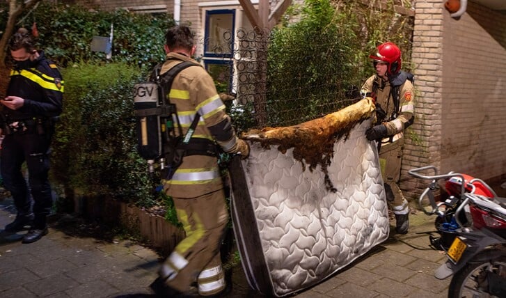 De brandweer sleept een matras naar buiten. De brand bleek mee te vallen.
