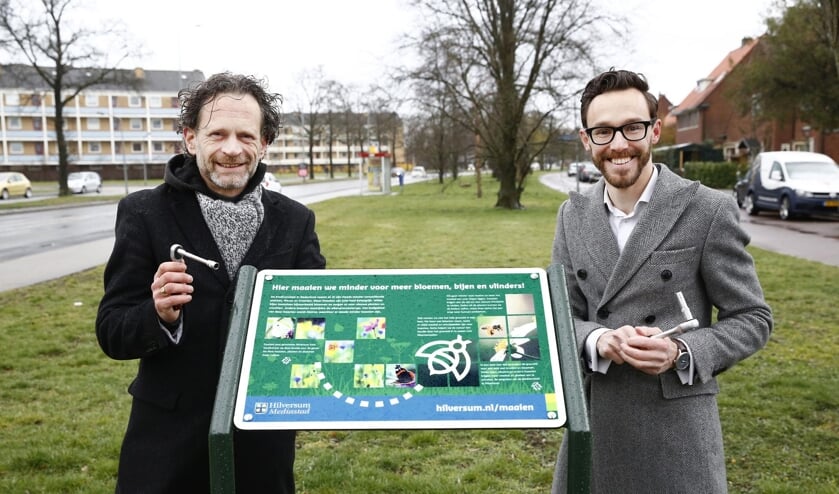 <p>Wethouders Bart Heller (links) en Arno Scheepers (rechts) bevestigen samen het eerste informatiebord 'Hier maaien we minder voor meer bloemen, bijen en vlinders!' </p>
