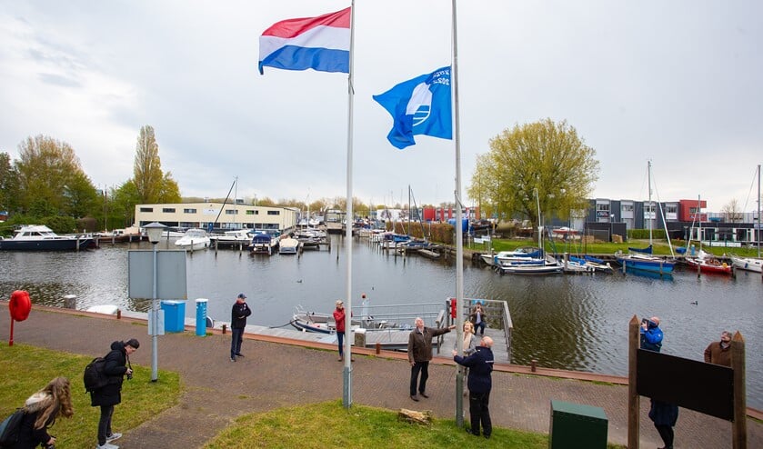 <p>De havenmeester hijst de blauwe vlag in de mast, onder toeziend oog van de wethouder en Patrick Poelmann.</p>