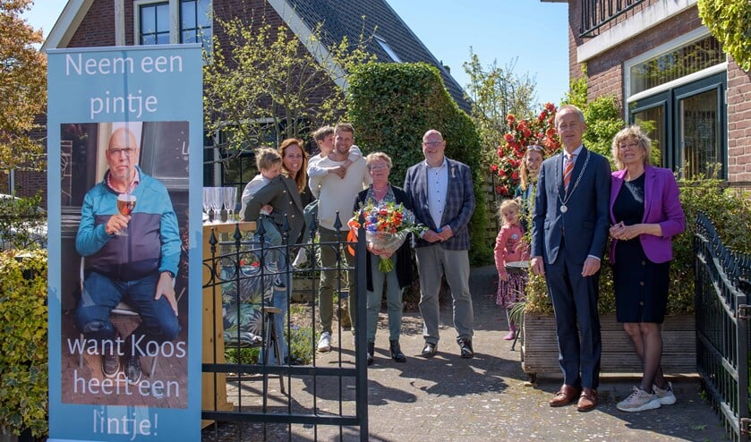 <p>Koos Drooger poseert bij de speciale banner die er voor hem was gemaakt.</p>