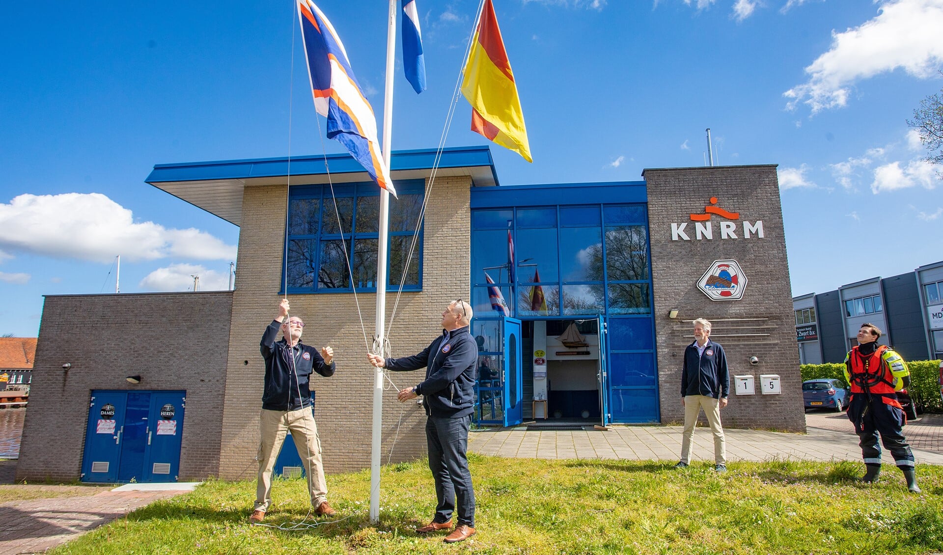 Frans van Tol (l) en Michiel Kok hijsen de KNRM vlag voor de botenloods.