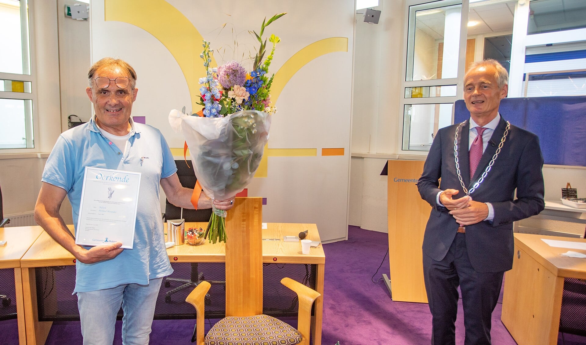 Roeland Bijlard met Huizer insigne, oorkonde en bos bloemen, die hij uit handen van burgemeester Niek Meijer kreeg.