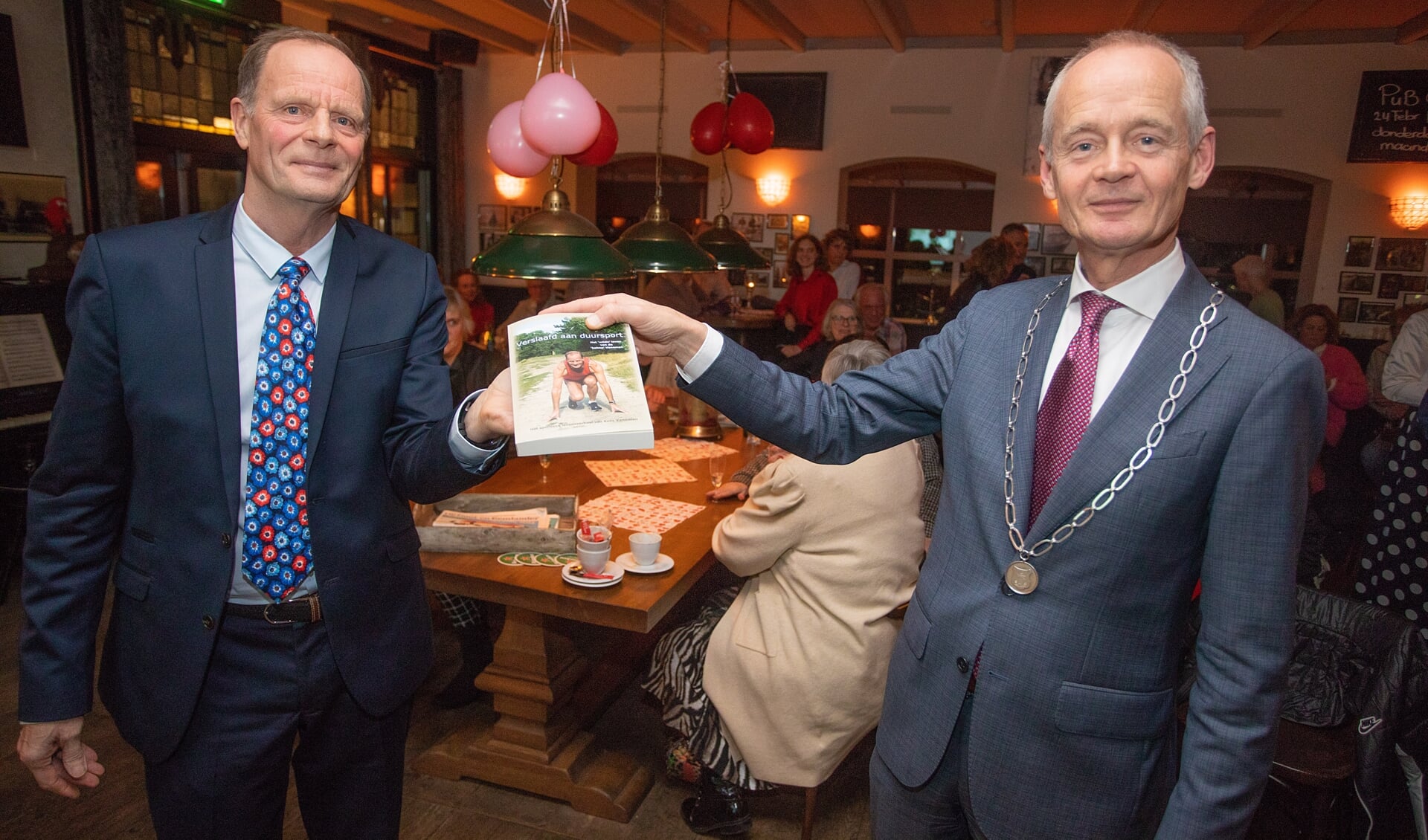 Kees Vaneman (l) overhandigt zijn boek aan burgemeester Niek Meijer.