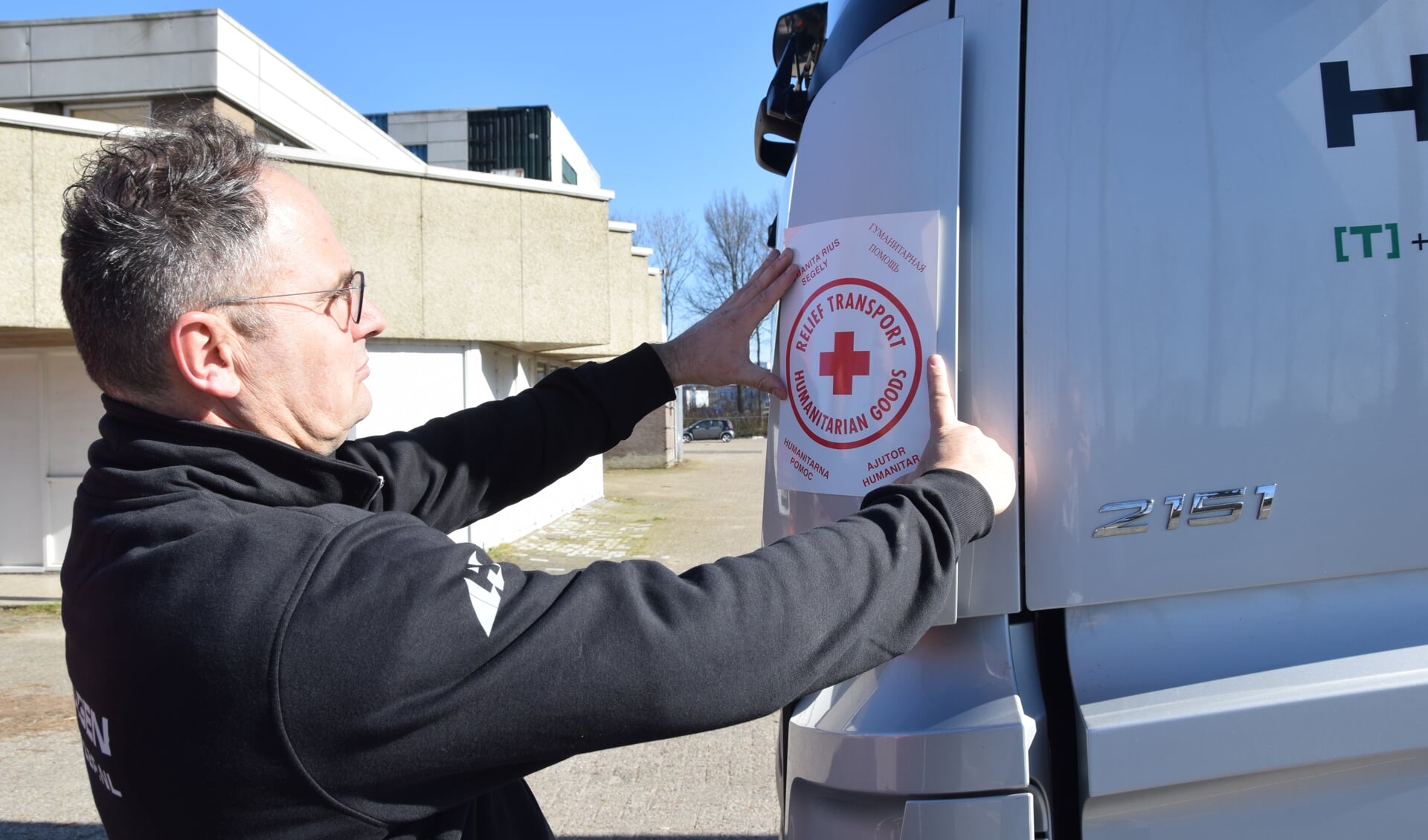 Robert Hagen plakt een sticker op zijn truck aan de hand waarvan instanties kunnen zien welke vracht hij rijdt richting de grens.