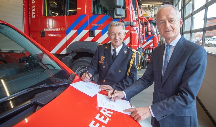 Brandweercommandant John van de Zwan (l) en burgemeester Niek Meijer ondertekenen de papieren.