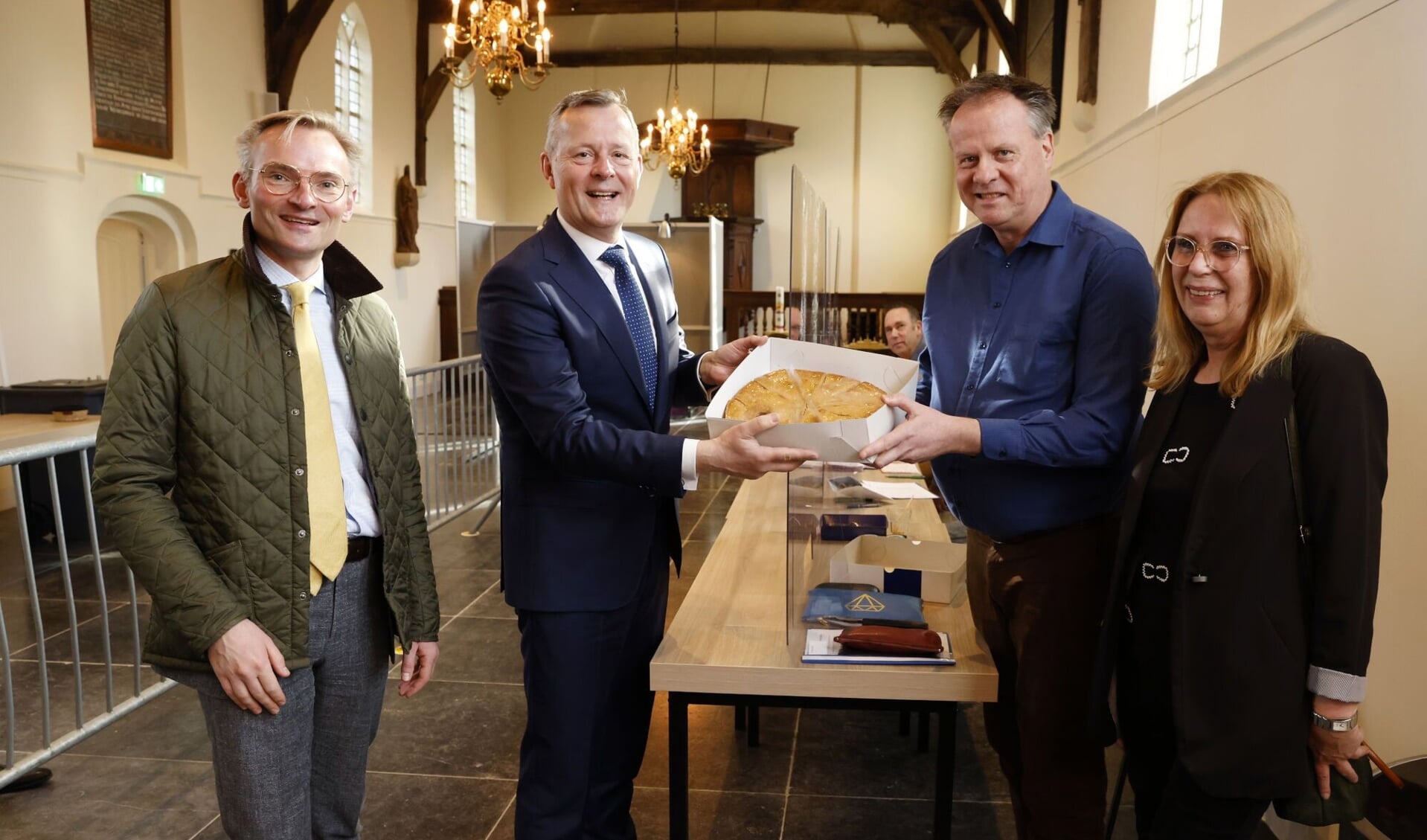 Burgemeester Nanning Mol (l) biedt met de Commissaris van de Koning taart aan.