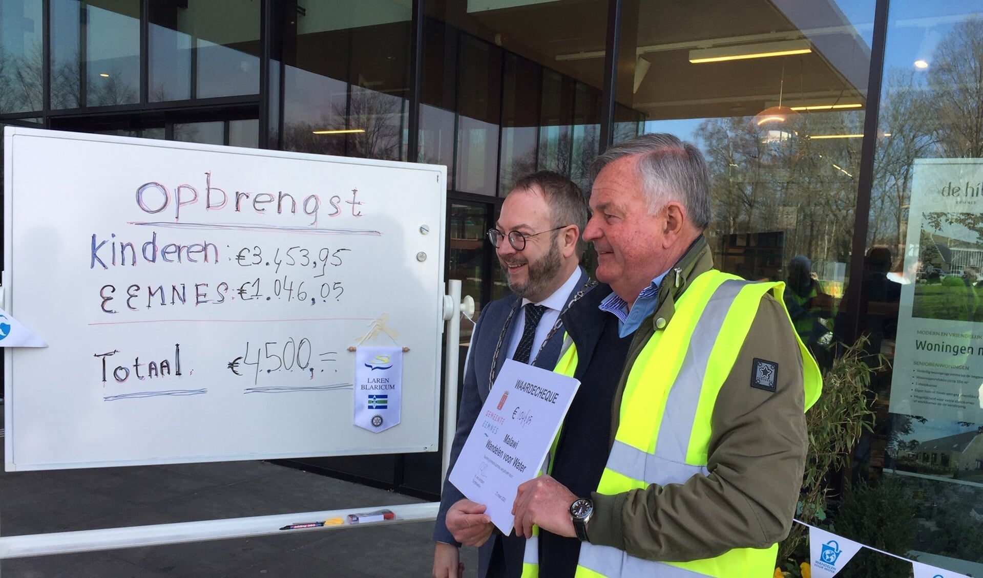 Burgemeester Roland van Benthem (links) en Pieter Verboom van Rotaryclub Laren-Blaricum maken de opbrengst bekend, die wordt aangevuld tot € 4.500