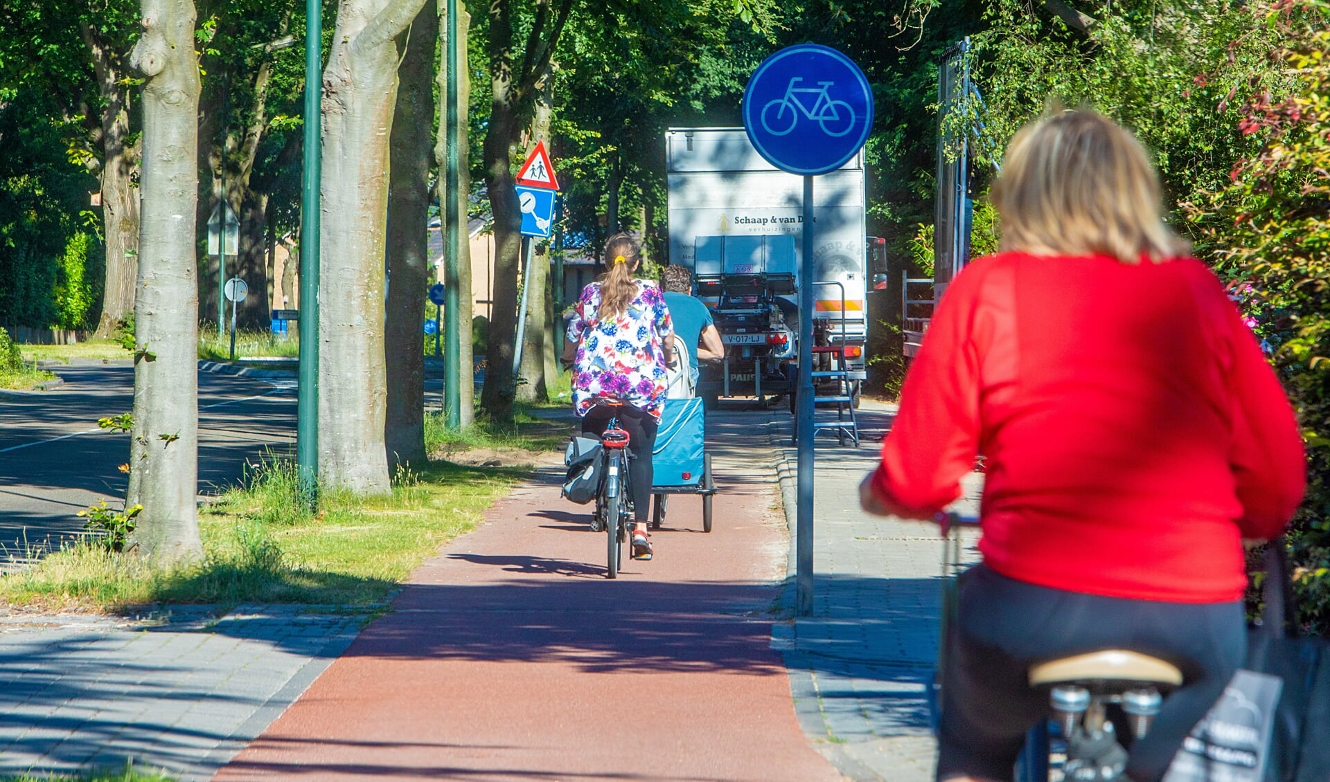 Busjes staan op de stoep en het fietspad geparkeerd. 