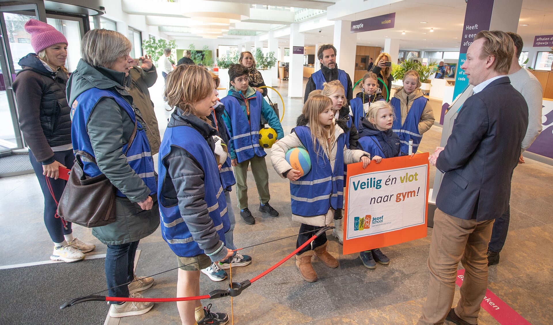 Wethouder Kruijt ontvangt de kinderen in het gemeentehuis. Vervolgens nam hij ze mee naar de raadszaal voor een 'lesje besturen'.