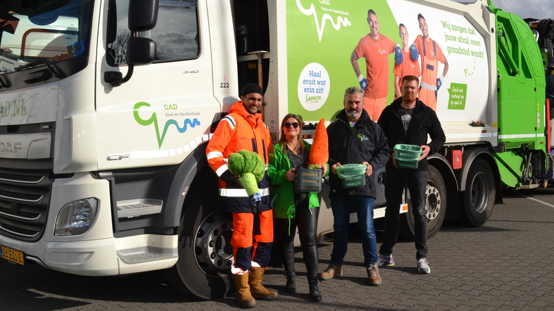 GAD-medewerkers Kurt, Boriska, Anto en Joey voor een vuilniswagen met campagnetekst.