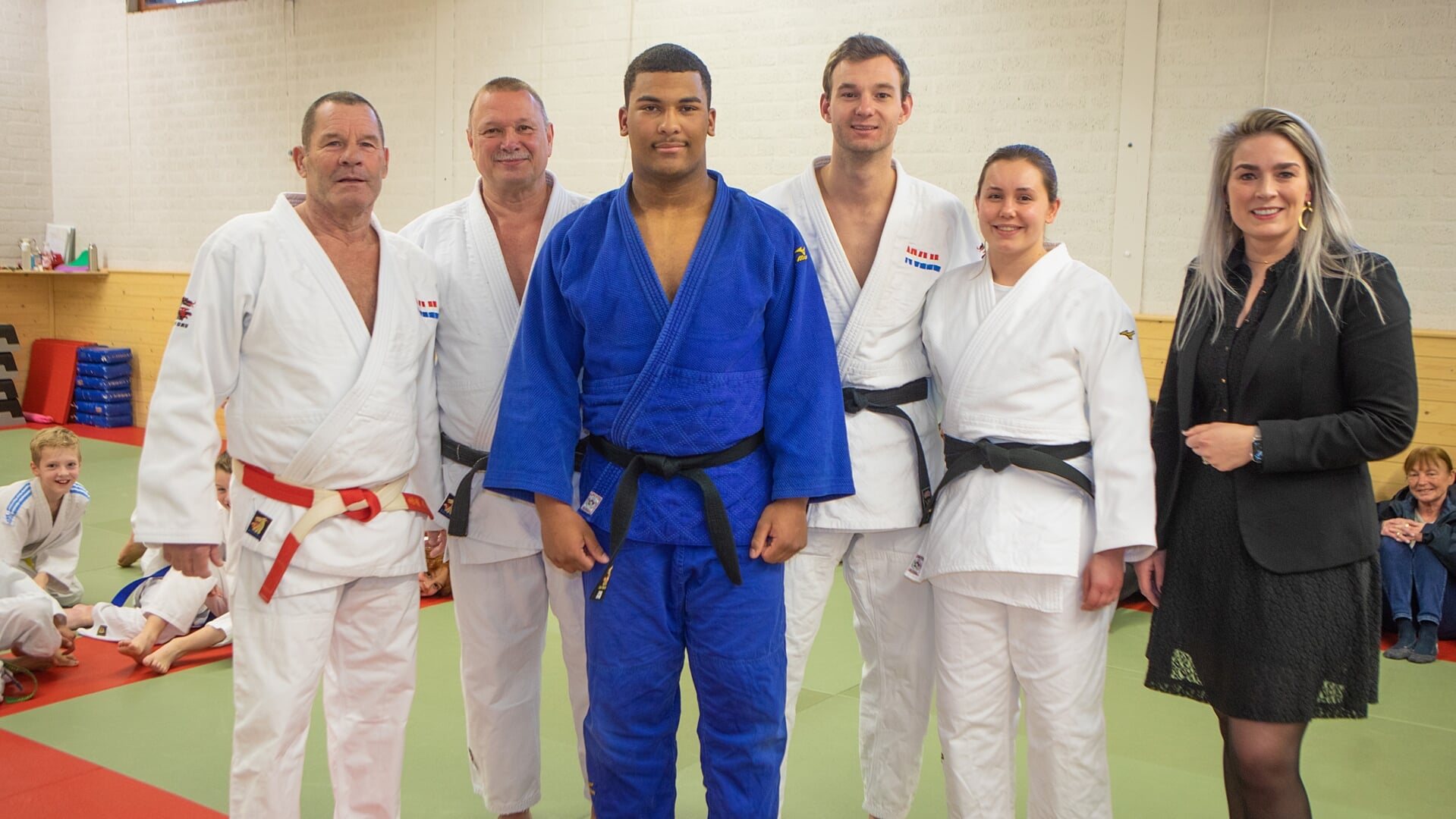 Judoka Dwayne (blauwe pak) kreeg het erelidmaatschap en de felicitaties van de wethouder (r).
