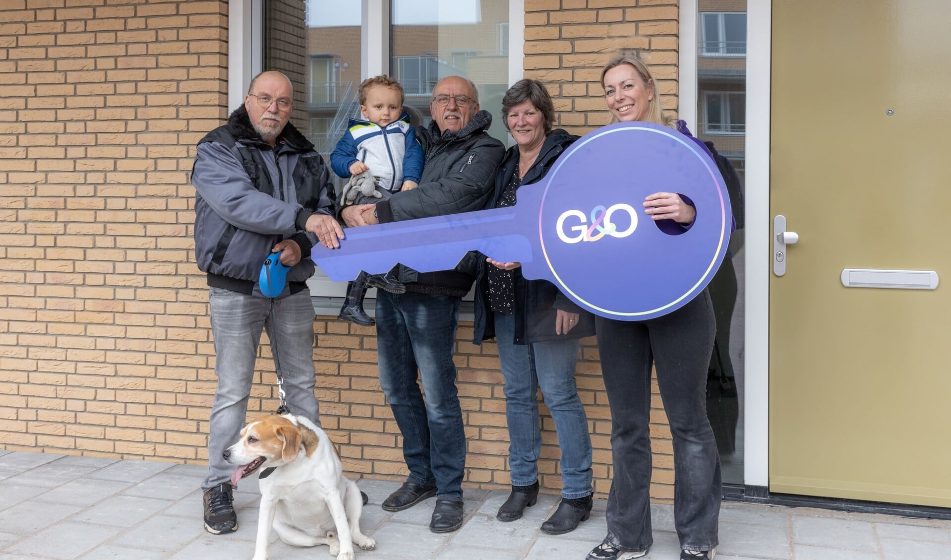 Familie Hamminga (boers, kleinzoon en vrouw) ontvangen symbolisch de sleutel van verhuurmakelaar Wanda (G&O).