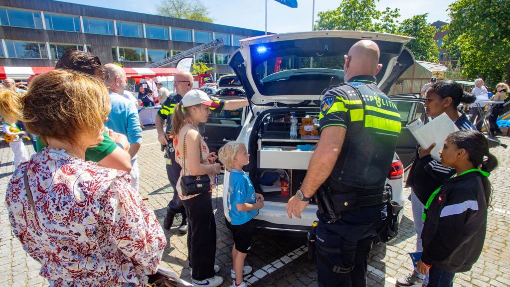 Kinderen staan nieuwsgierig te kijken in de politieauto 