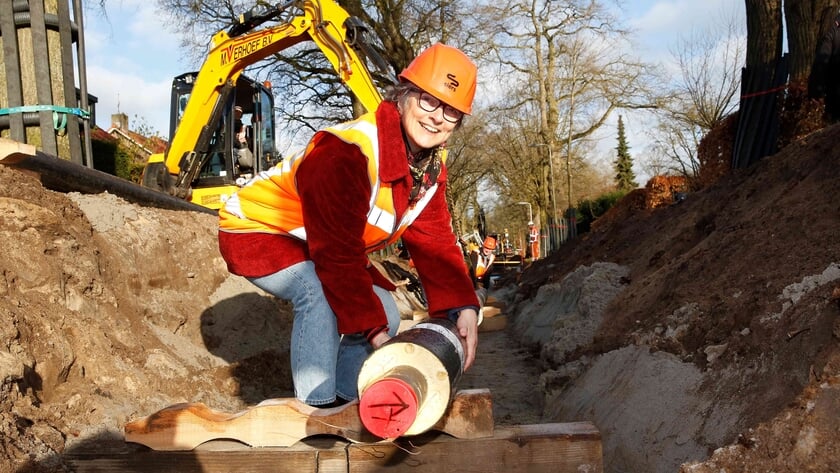 Wethouder Barbara Boudewijnse legt een buis voor WarmtenetMuiderberg-Wattnu.