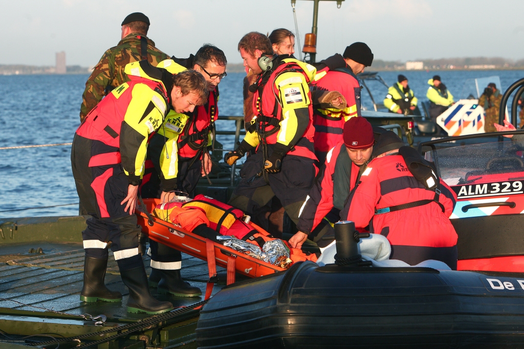 Een van de slachtoffers wordt in een schepbrancard op een reddingsboot getild.