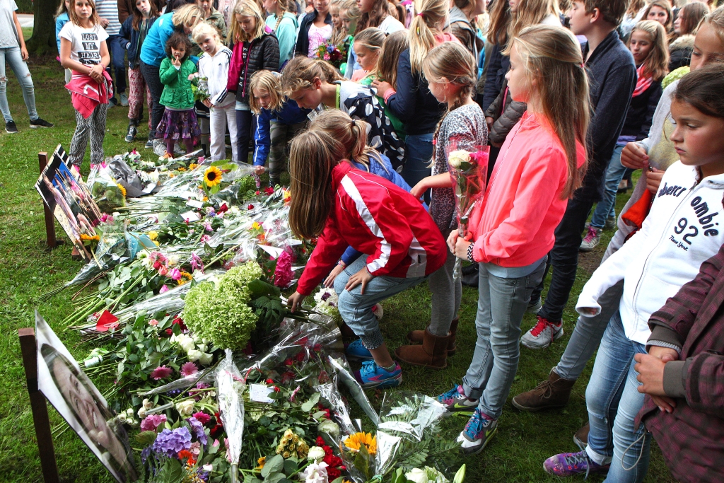 Deelnemers aan de stille tocht leggen bloemen bij de foto's van de slachtoffers. 