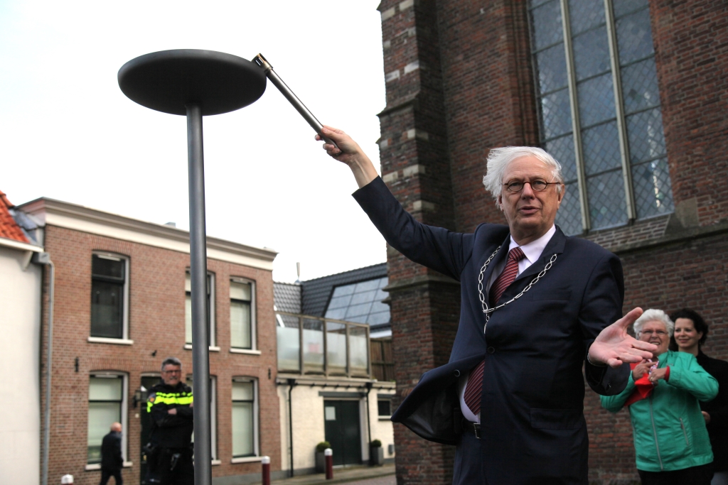 Burgemeester Van Bochove krijgt door de windvlagen het vrijheidsvuur niet aan. 