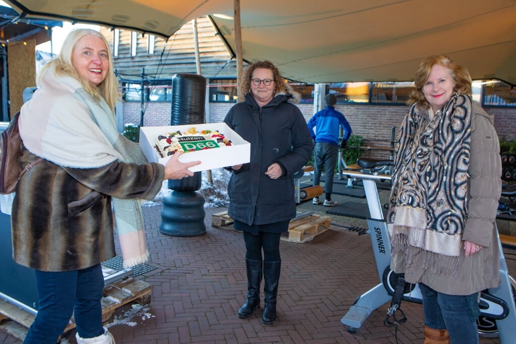 Karin van Werven (l) overhandigt samen met Marlous Verbeek (r) de taart aan Pauline Rebel.