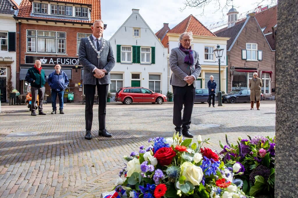 De burgemeester legt samen met Jan Landsaat bloemen bij het Comeniusbeeld.