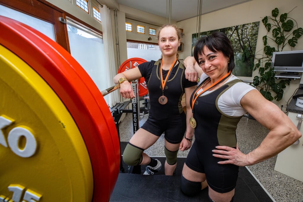 Cathelijne Gort (achter) en Christine Rebello laten hun NK-medailles zien in de home gym van de master. 