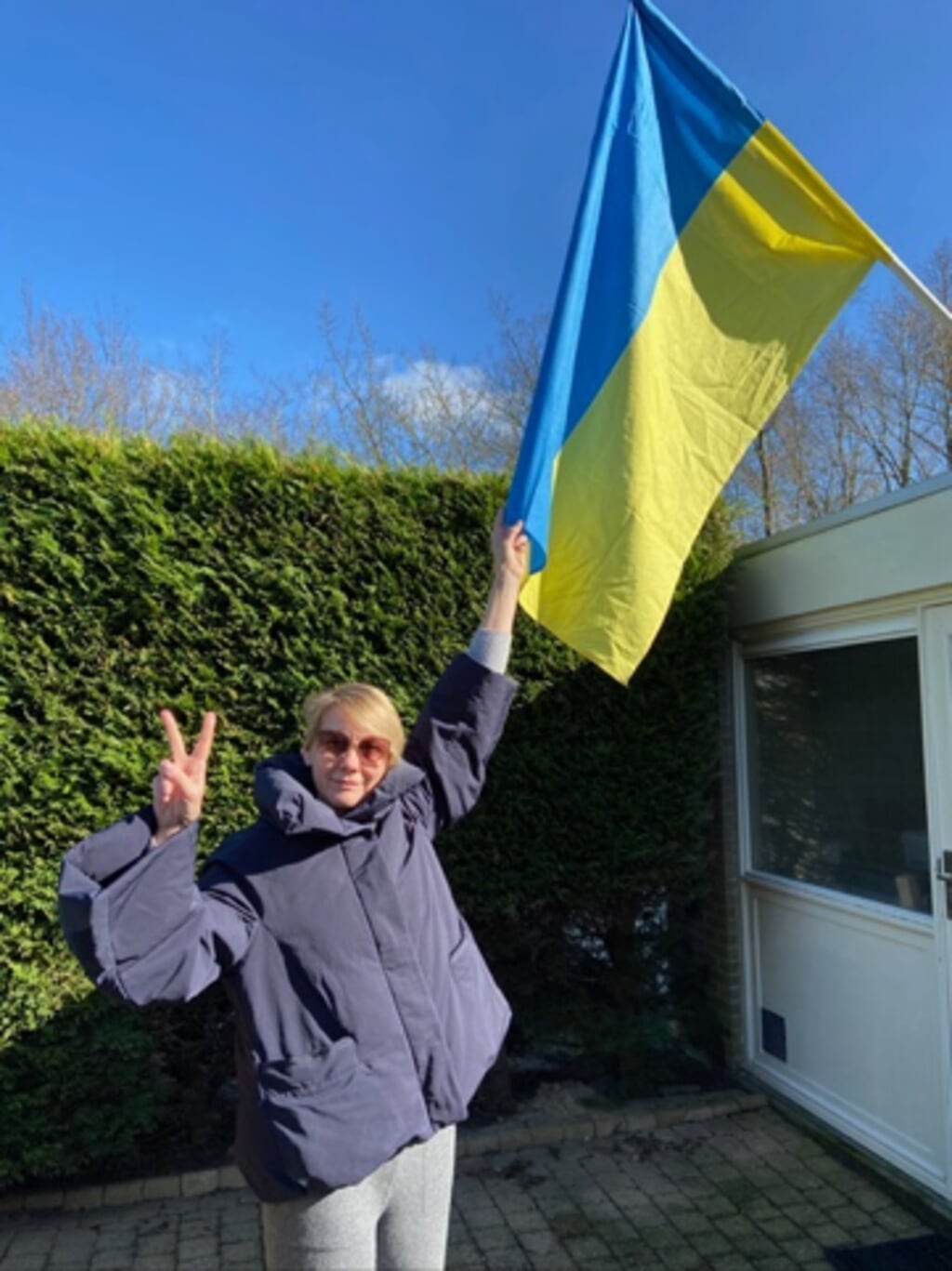 Valeriya met Oekraïense vlag voor haar huis in Naarderbos.