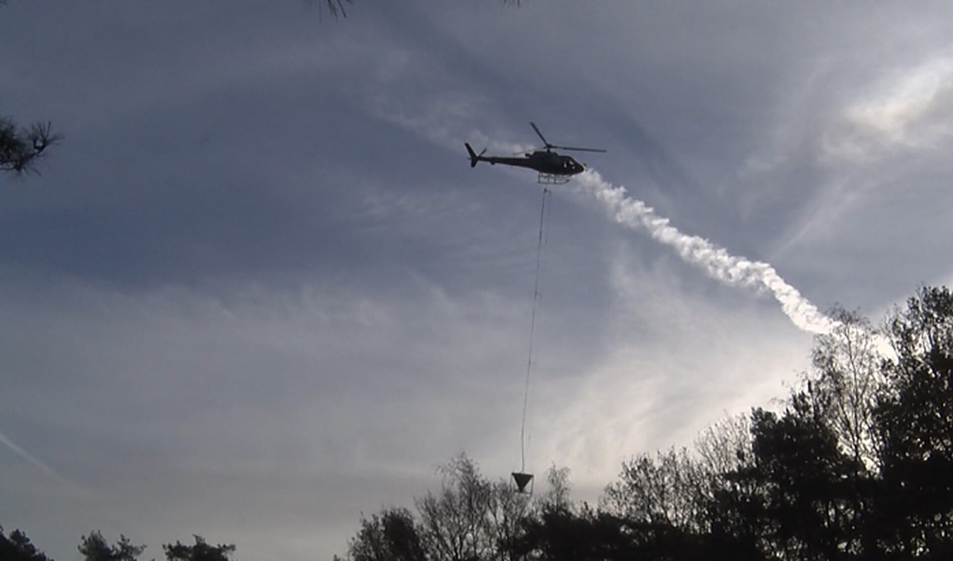 Met behulp van een helikopter wordt het steenmeel over De Malpie verspreid.
