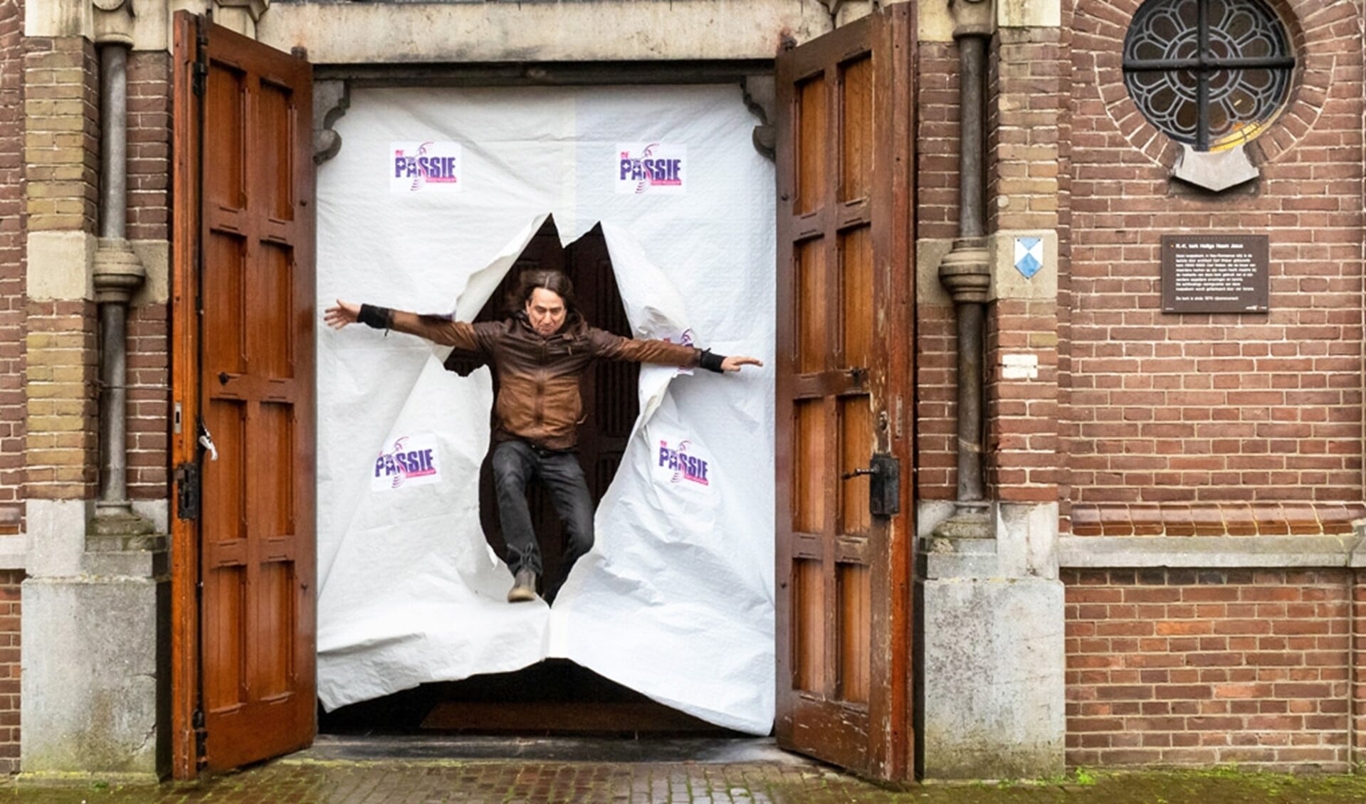 Mari Maas springt symbolisch door de deuren van de Koepelkerk in Lierop. Dit jaar vindt het evenement buiten plaats.