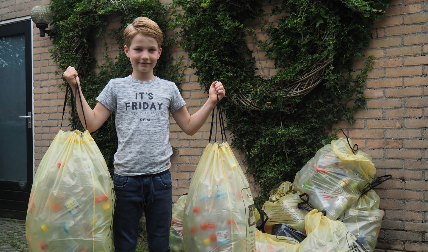 Tim van der Lugt (8) met zijn 9 zakken plastic flessen die hij het afgelopen jaar heeft verzameld. 