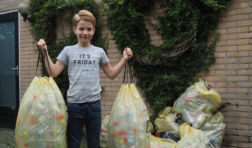 <p>Tim van der Lugt (8) met zijn 9 zakken plastic flessen die hij het afgelopen jaar heeft verzameld. </p>
