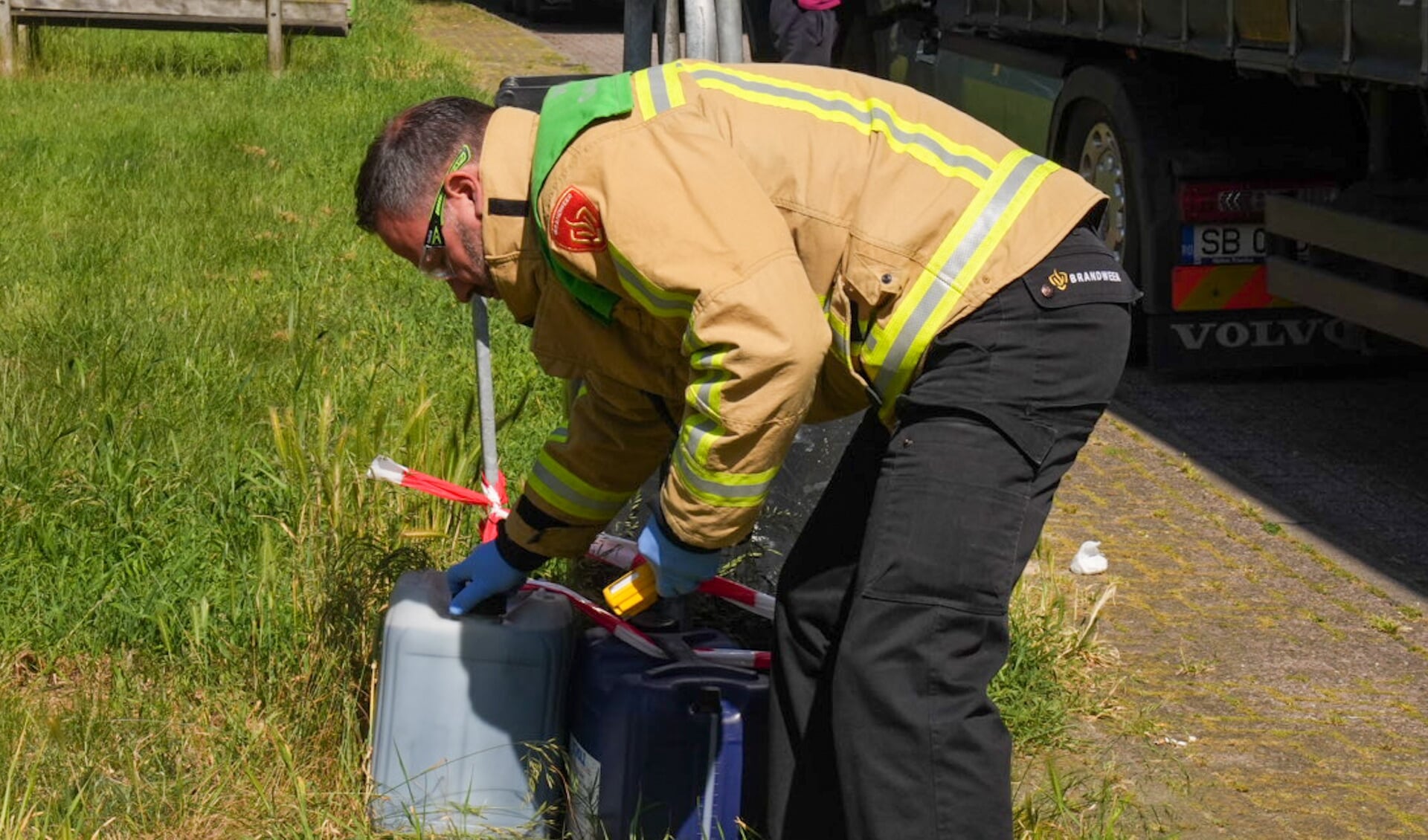 Een officier van de brandweer gespecialiseerd in gevaarlijke stoffen controleert de gedumpte jerrycans. (Foto: Harrie Grijseels/112Nieuwsonline)