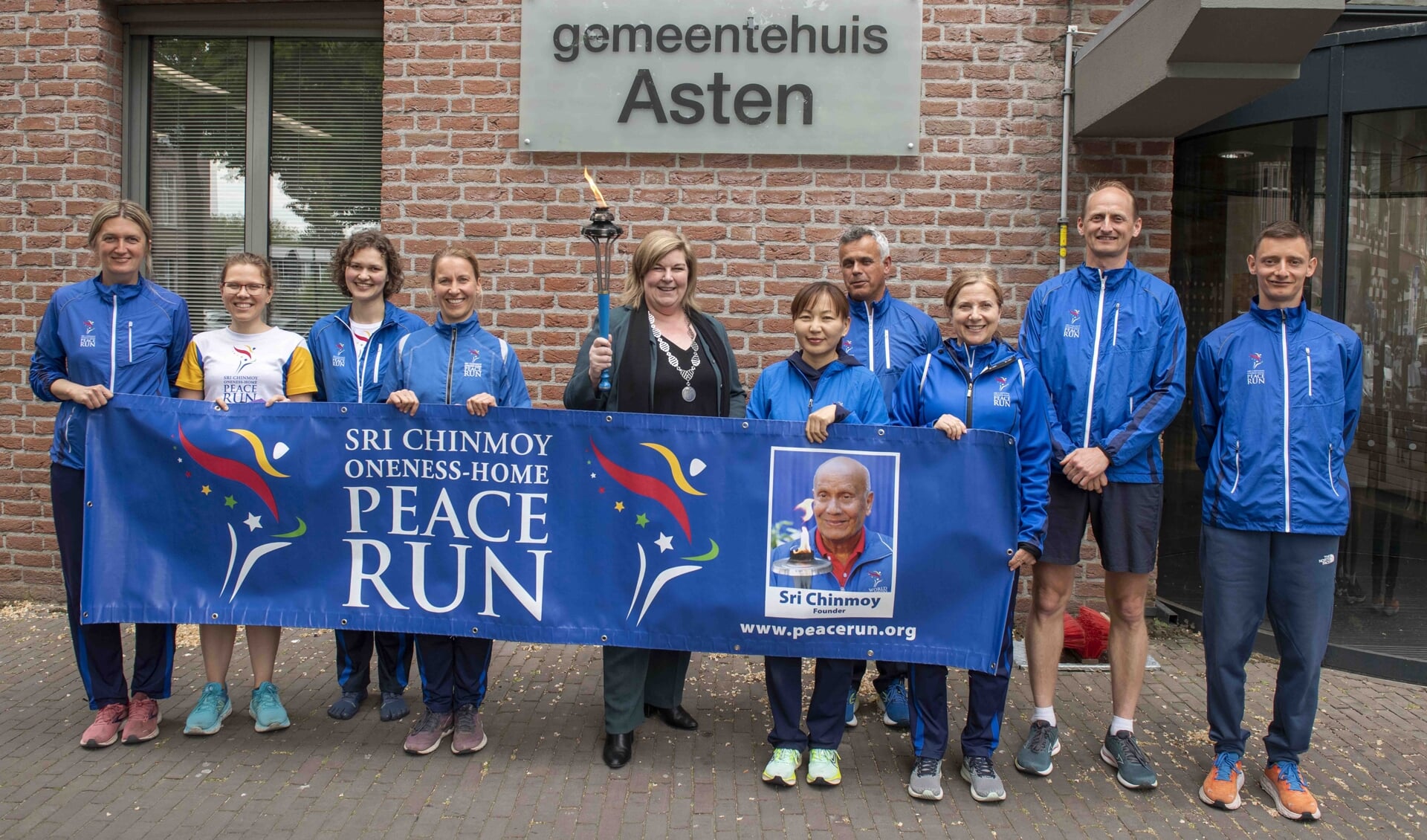 Het internationale team van de Peace Run met in het midden wethouder Janine Spoor die de vredesfakkel draagt. (Foto: Hein van Bakel)