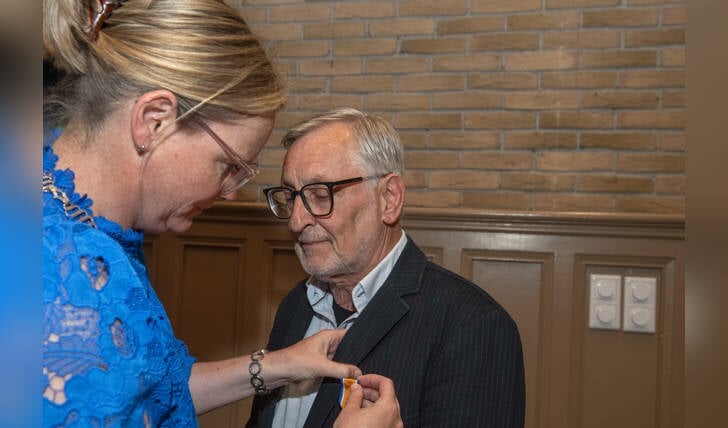 Burgemeester Anke van Extel-van Katwijk spelt de Koninklijke onderscheiding op bij Math Vankan. (Foto: Hein van Bakel)