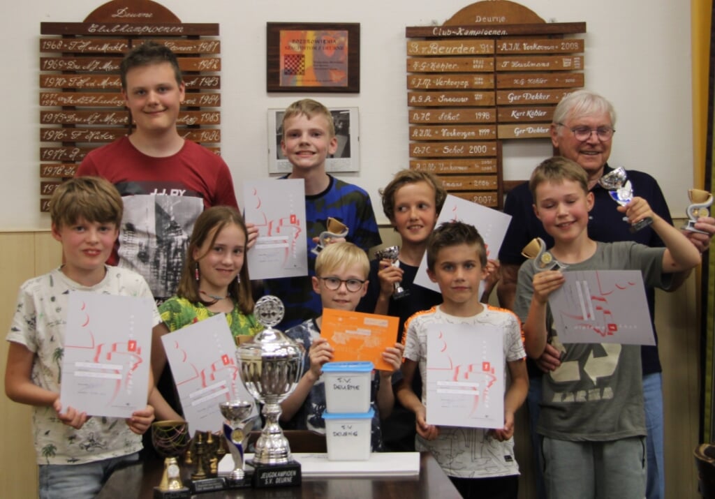 Jip Versteeg met voor zich de gewonnen bekers samen met de andere deelnemers van Schaakvereniging Deurne.
