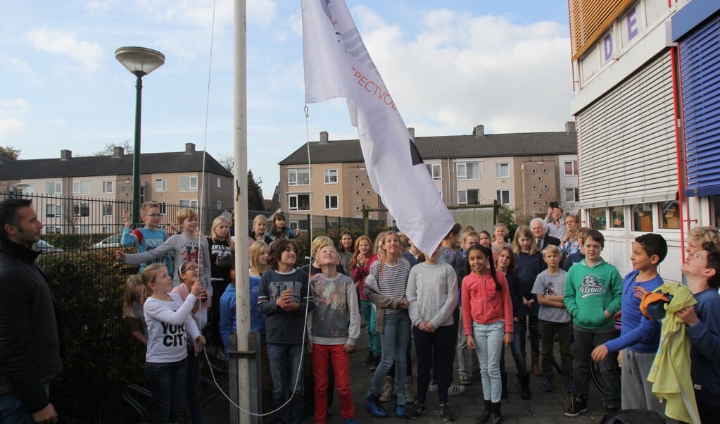 De vlag wordt onder grote belangstelling van de leerlingen en gastdocent Karel Beesemer gehesen. [foto Reyn Schuurman]