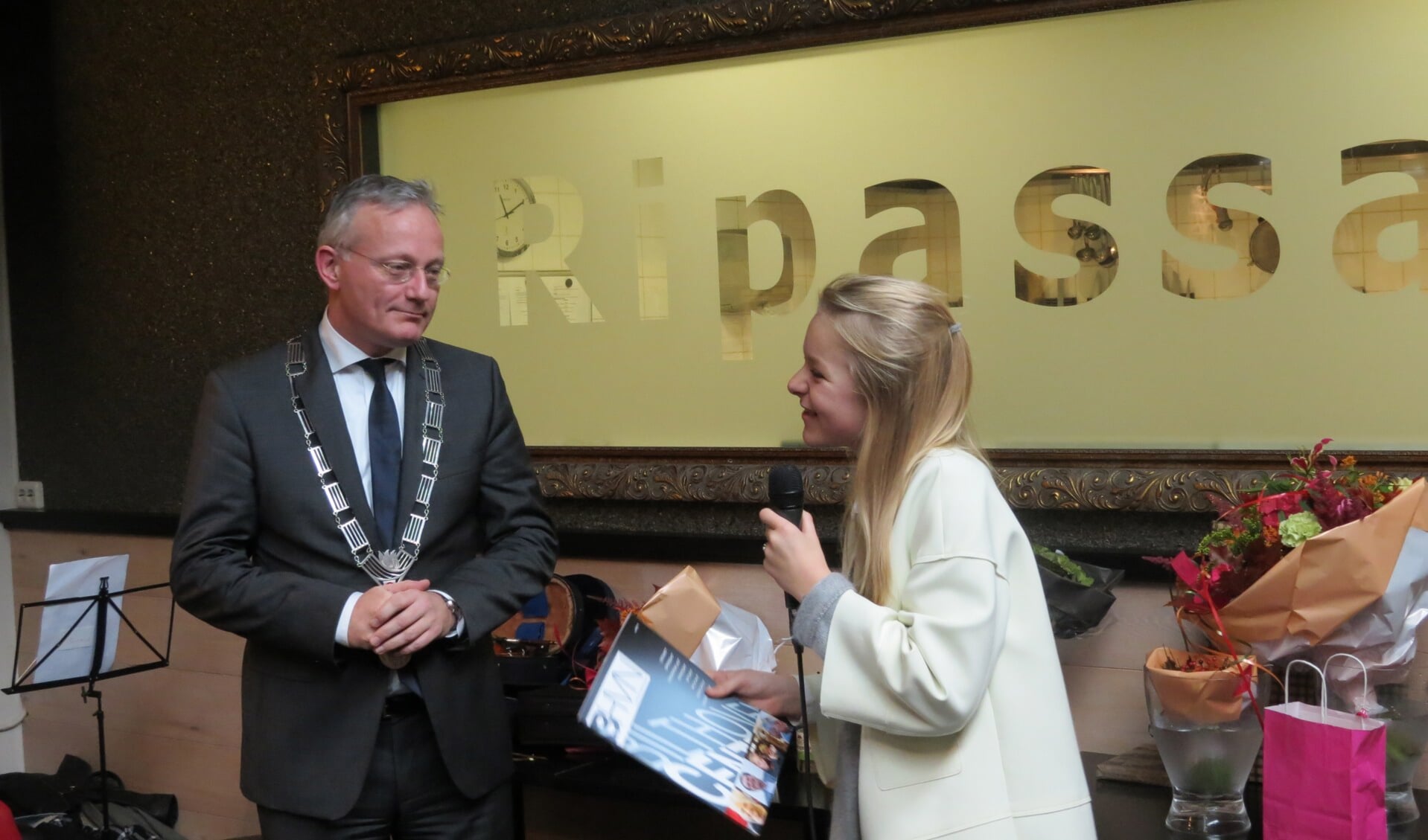 Burgermeester Arjen Gerritsen krijgt het eerste exemplaar aangeboden door Sita Knegjens.