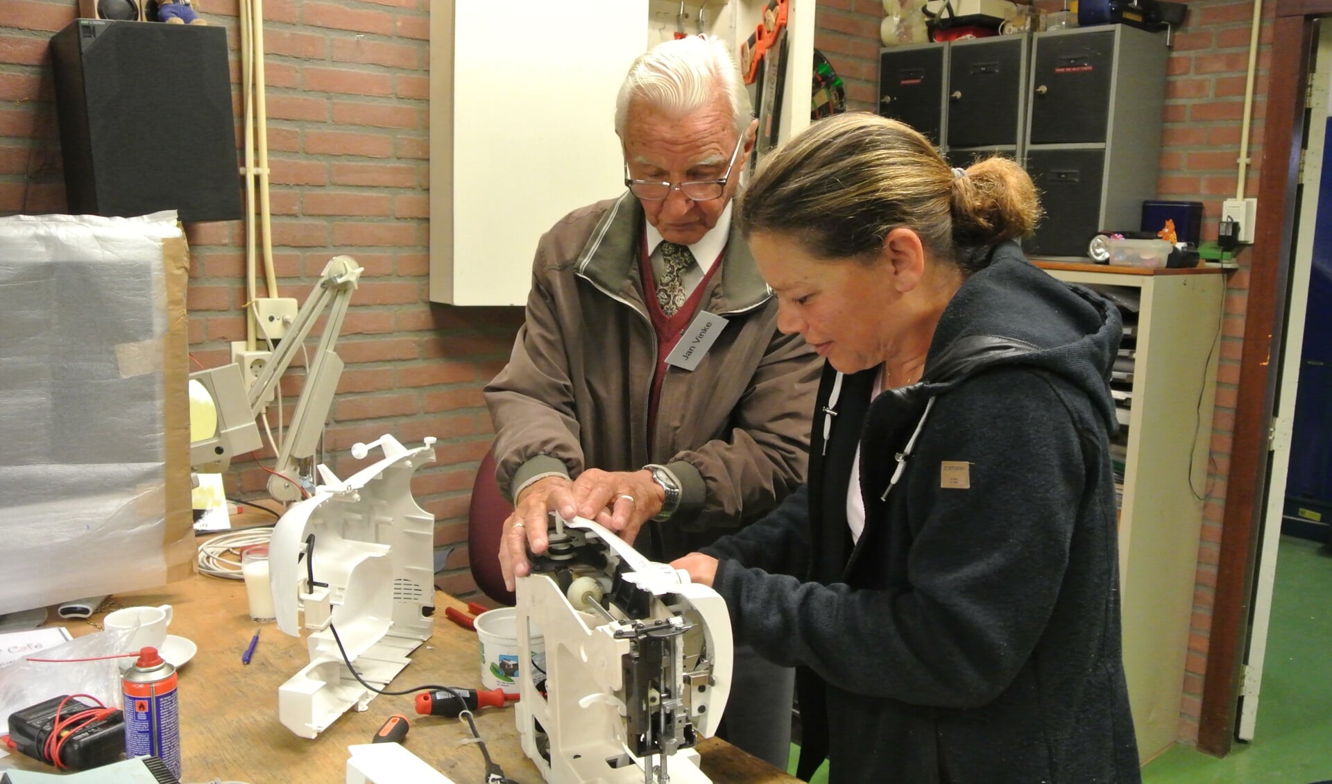 Reparateur Jan Vinke neemt een naaimachine met kapotte motor onder de loep (foto Frans Poot).