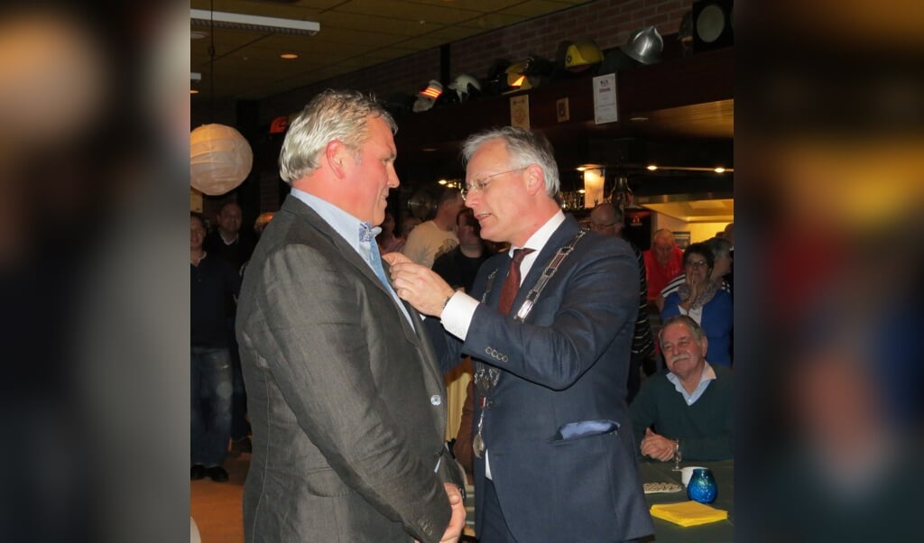 Wout Hazeleger krijgt de onderscheiding opgespeld door de burgemeester.