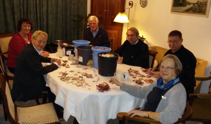 Lions nijver waardepunten tellend bijeen. De emmers waarin de diverse soorten punten worden verzameld staan op tafel.