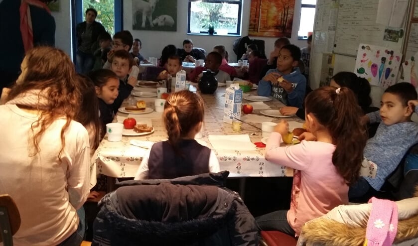 Terwijl de lammetjes toekijken genieten de basisscholieren van het ontbijt met appel en komkommer en halfvolle melk.