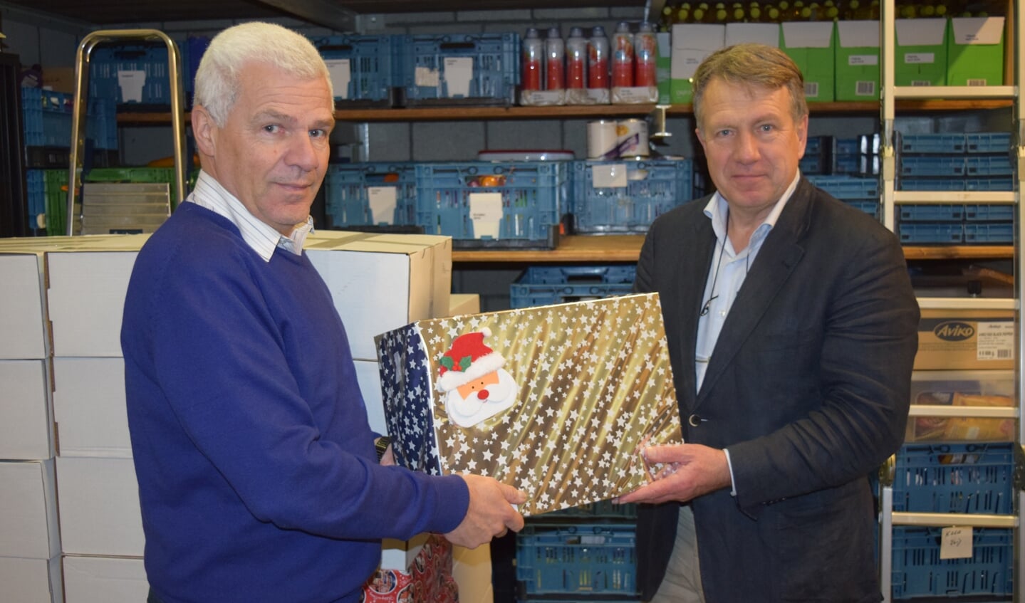 Klaas Kuiken (r) overhandigt het eerste kerstpakket aan Rob Veerman.