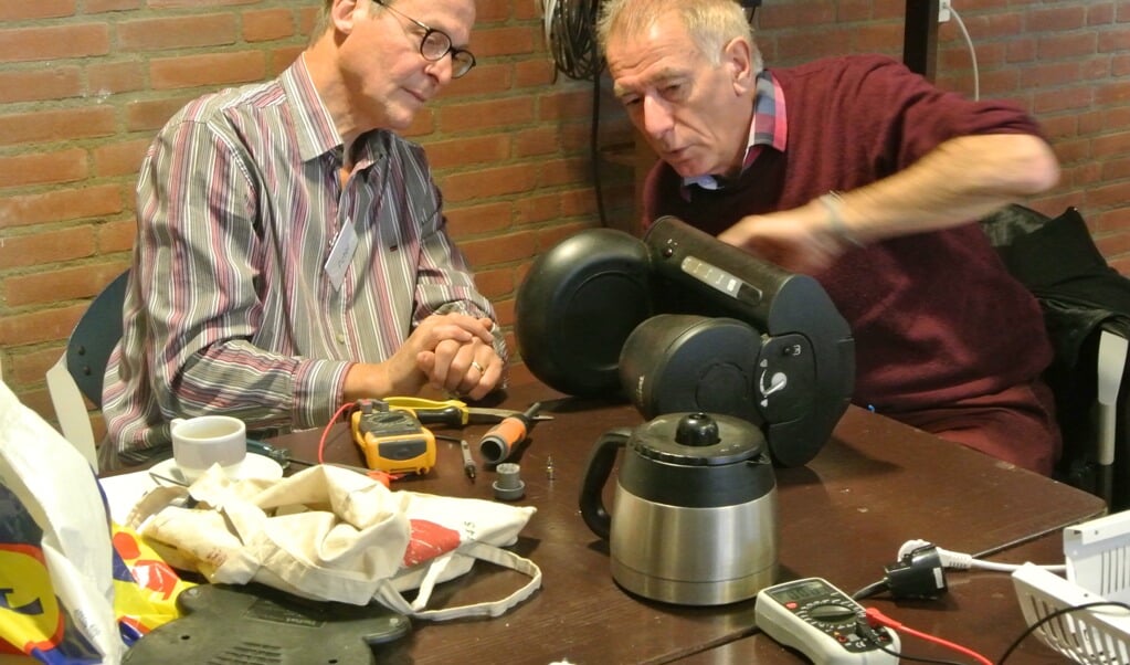 Henk Zandvliet (rechts) onderzocht zijn koffiezetter met behulp van reparateur Peter. Er bleek slechts een nieuwe zekering nodig om het apparaat weer te laten werken.