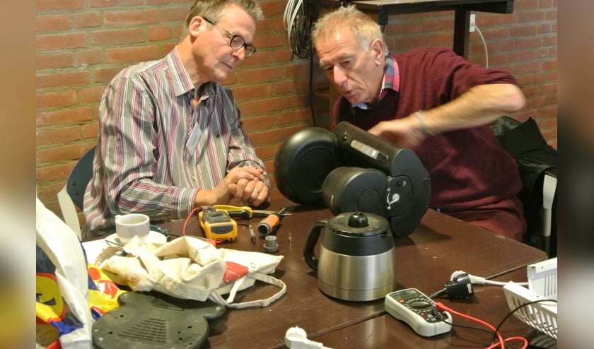 Henk Zandvliet (rechts) onderzocht zijn koffiezetter met behulp van reparateur Peter. Er bleek slechts een nieuwe zekering nodig om het apparaat weer te laten werken.