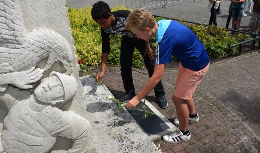 Leerlingen leggen bloemen bij het monument.