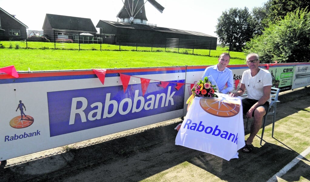?(Links) Benjamin Gerritsen van de Rabobank voor het reclamebord van de Rabobank.