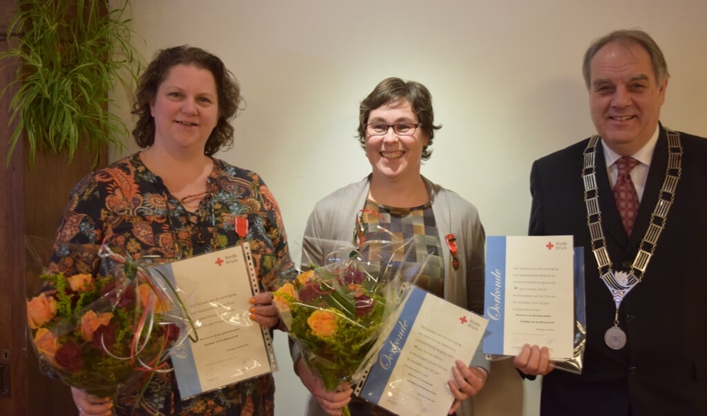 Drie vrijwilligers van het Rode Kruis werden tijdens de nieuwjaarsreceptie in de bloemetjes gezet: v.l.n.r. Marrigje van der Grift en Janneke Lam. Burgemeester Verkerk verving even de afwezige Annelies van Heeringen.