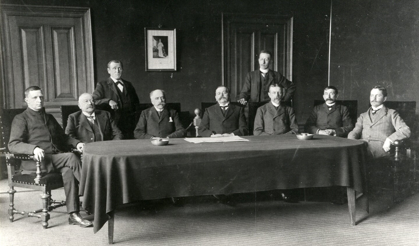 Een foto van de gemeenteraad van 1909 -1911, allen in stemmige kleding poserend. Zittend v.I.n.r. S. Floor (1900-1911) r.lid; Jhr. Mr. D. de Blocq van Haersma de With (1879-1907) burgerm. en (1882-1915) r.lid; M. v. Marwijck Kooij (1895-1913) r.lid; H. Ph. J. baron 
van Heemstra (1907-1927) burgem.; Mr. J.E.W. Twiss (1887-1917) r.lid.; P.N. Hoogland (1905-1931) r.lid; C.L. baron van Boetzelaer (1900-1931) r.lid. Staand (l) T. Meijer (1900-19