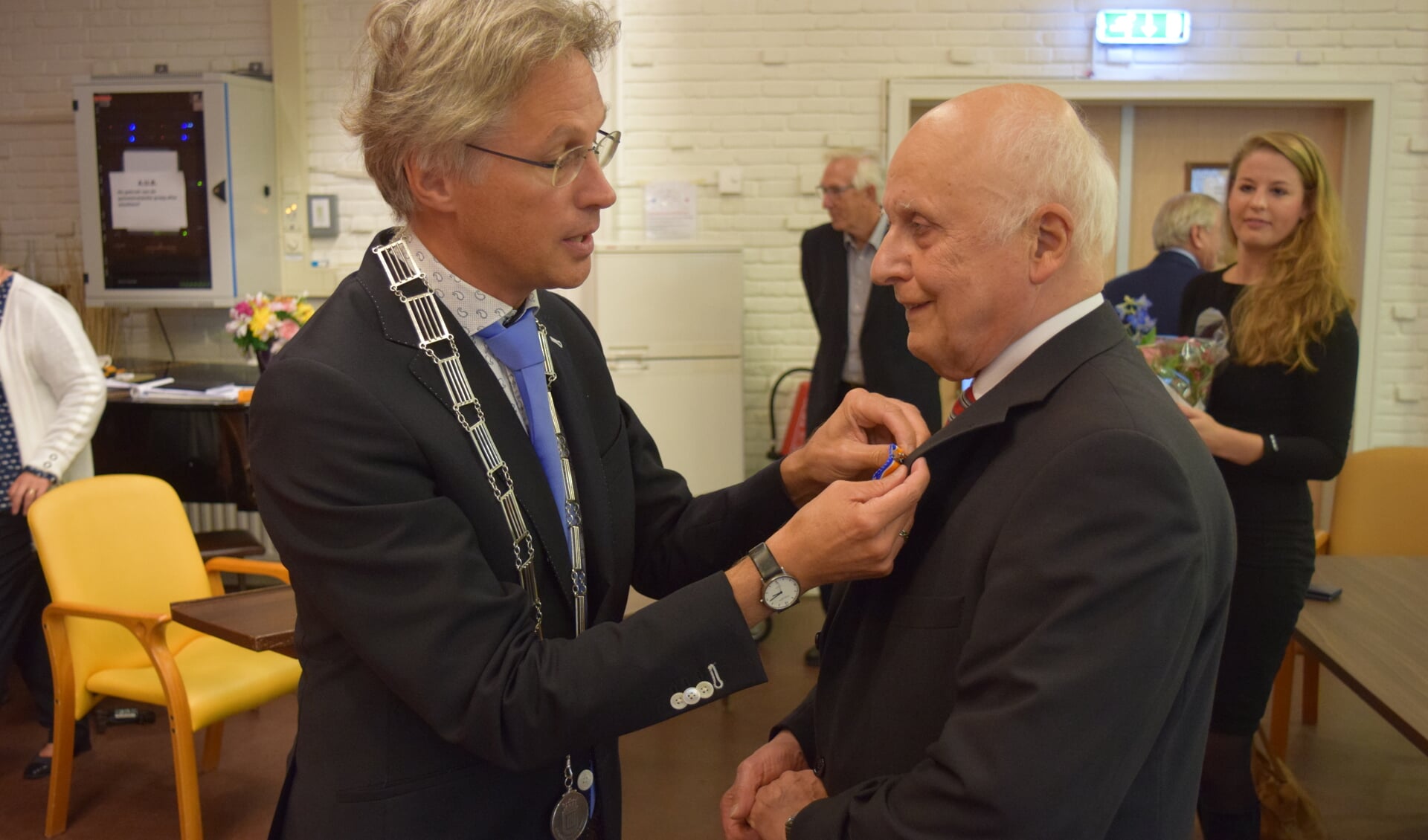  Locoburgemeester Hans Mieras speldt de Koninklijke Onderscheiding bij de heer Van der Linden op.