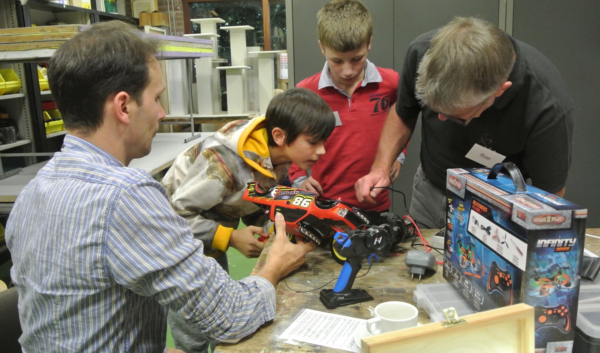 V.l.n.r. Vader Rene kijkt hoe zijn zoon Salomé samen met reparateurs Pieter en Roel de radio bestuurbare auto onderzoekt. (foto Frans Poot)