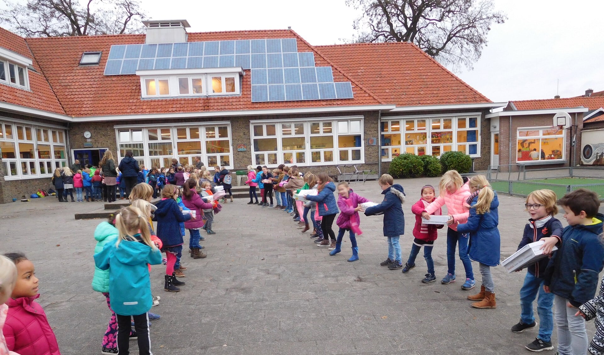 Kinderen van de Groen van Prinstererschool geven de gevulde dozen door op weg naar kinderen die het veel minder hebben.