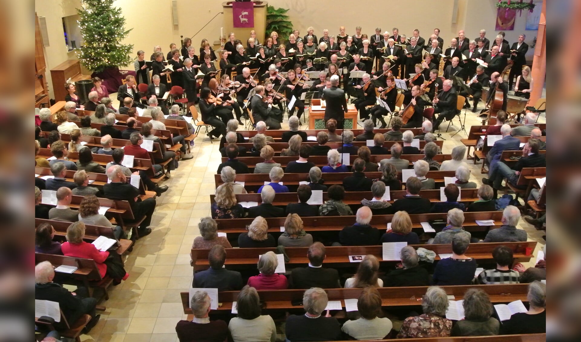  Het koor, orkest en solisten in een volle kerk 